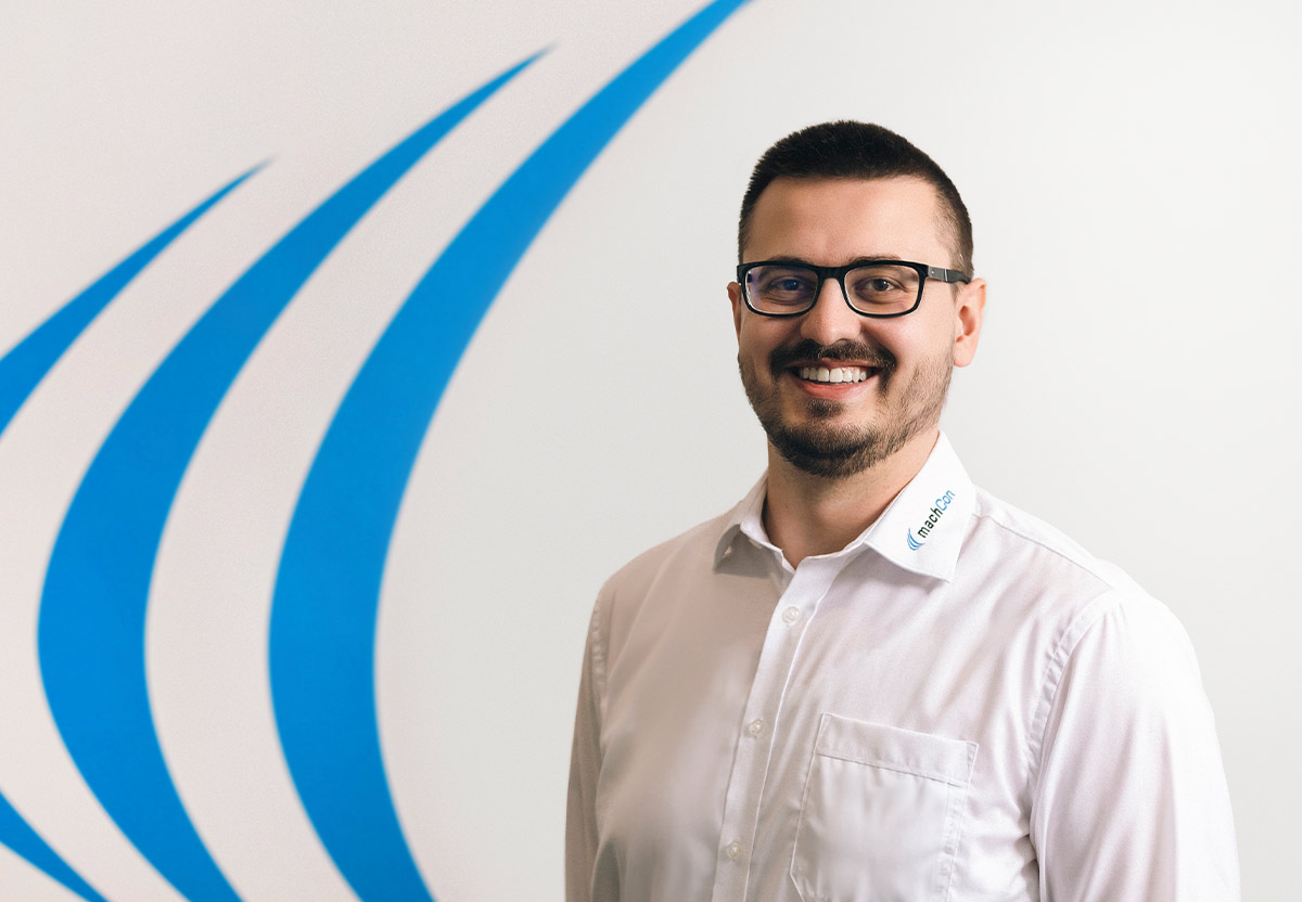 Person steht vor einer weißen Wand mit dem machCon Logo 